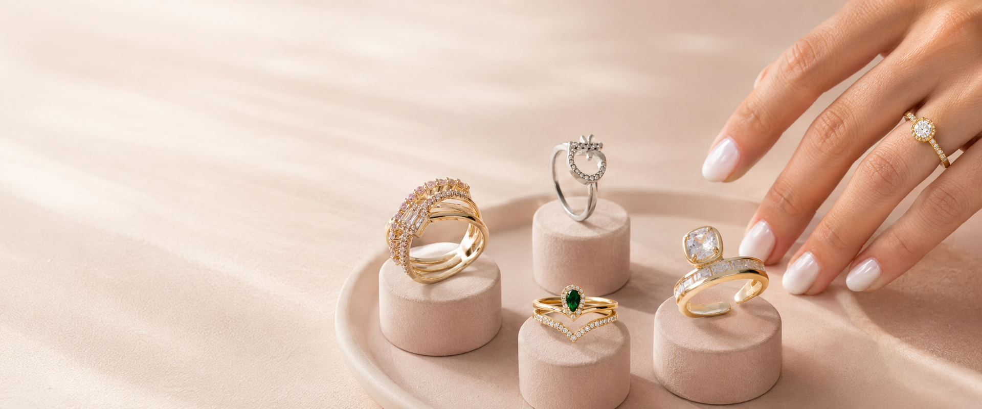 Anillos AMR Joyería sobre bases rosadas con una mano femenina